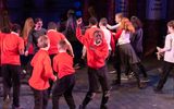 A group of primary school children running and dancing on a theatre stage.
