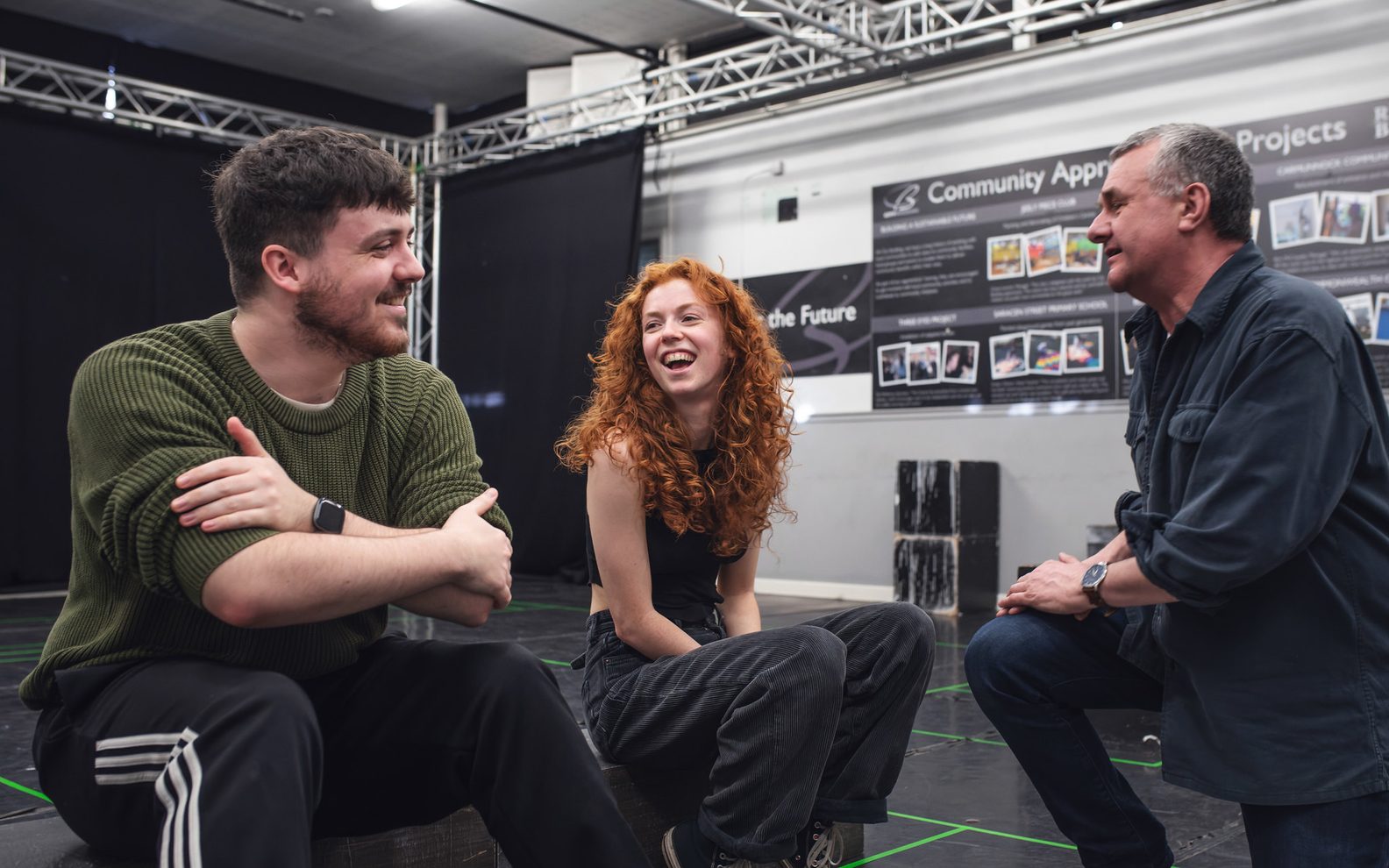 Three people rehearsing for a show. They are smiling.