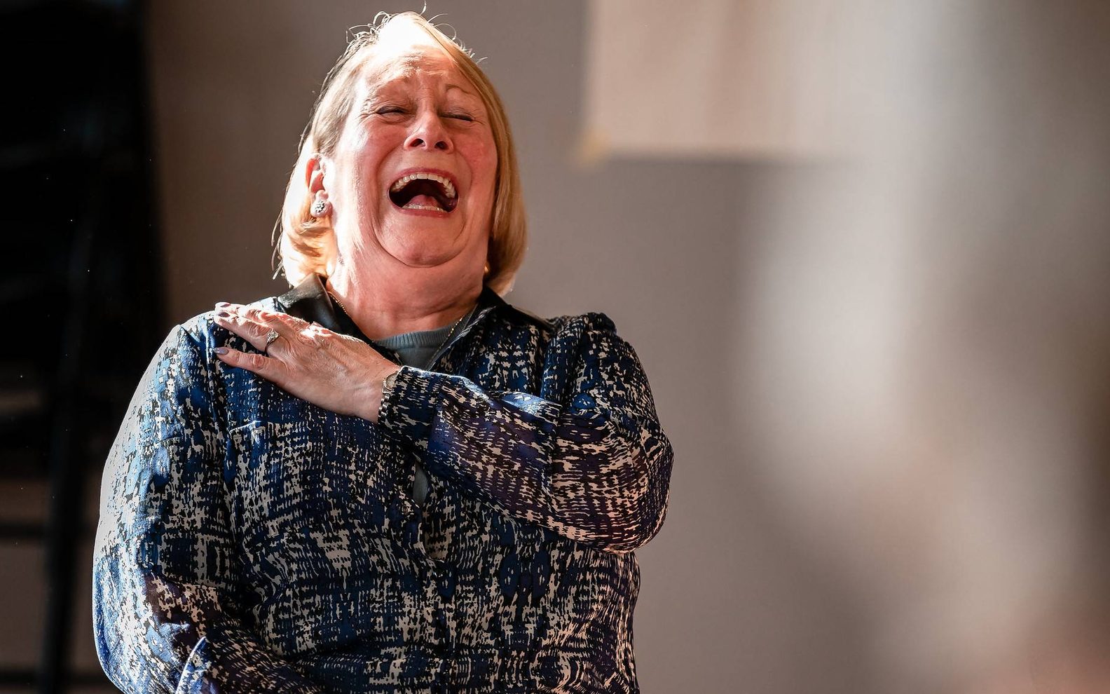 An older woman laughing openly.