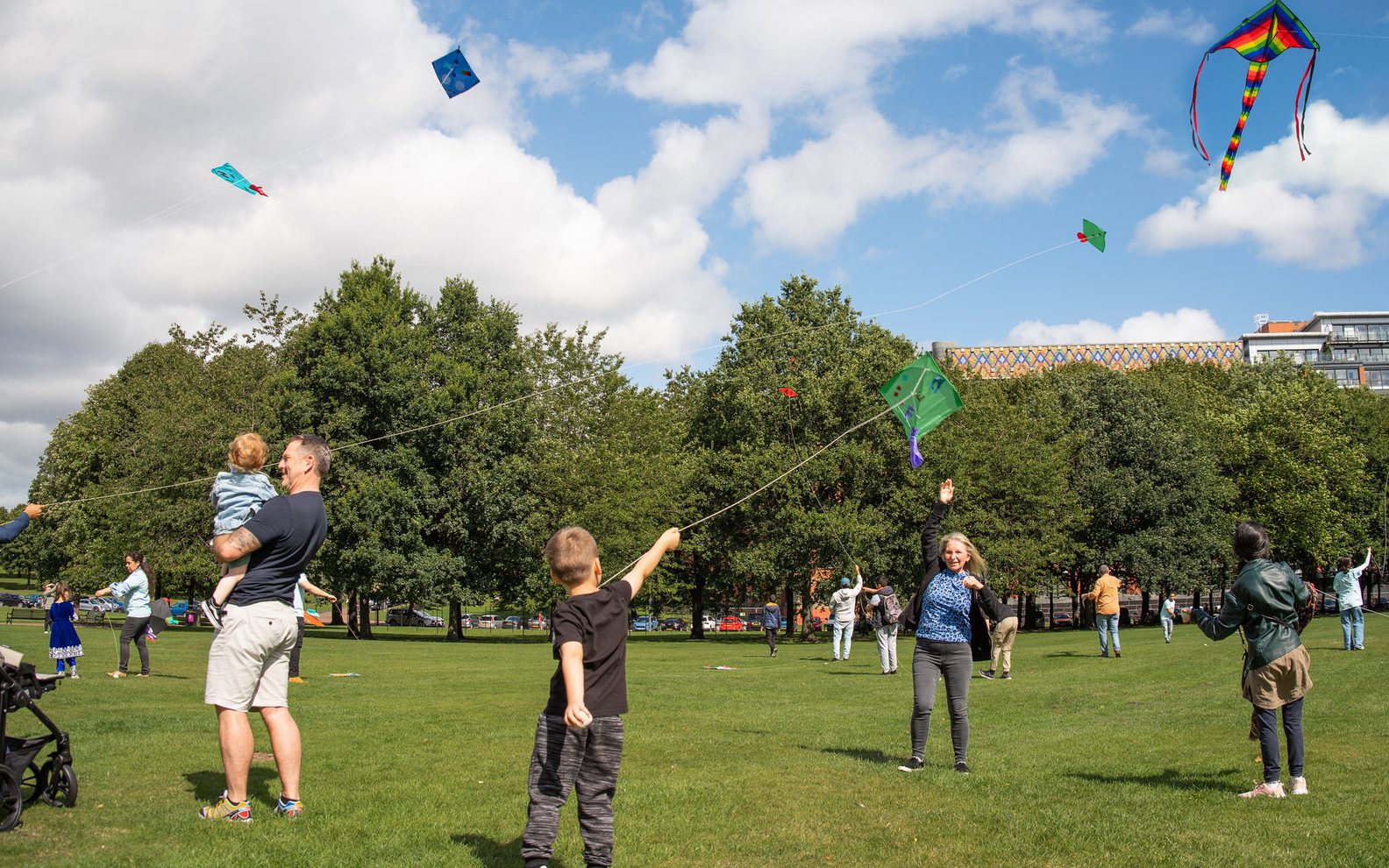 Several people in a park flying kites.