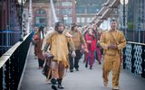 A large group of people walking across South Portland Street suspension bridge in Glasgow.