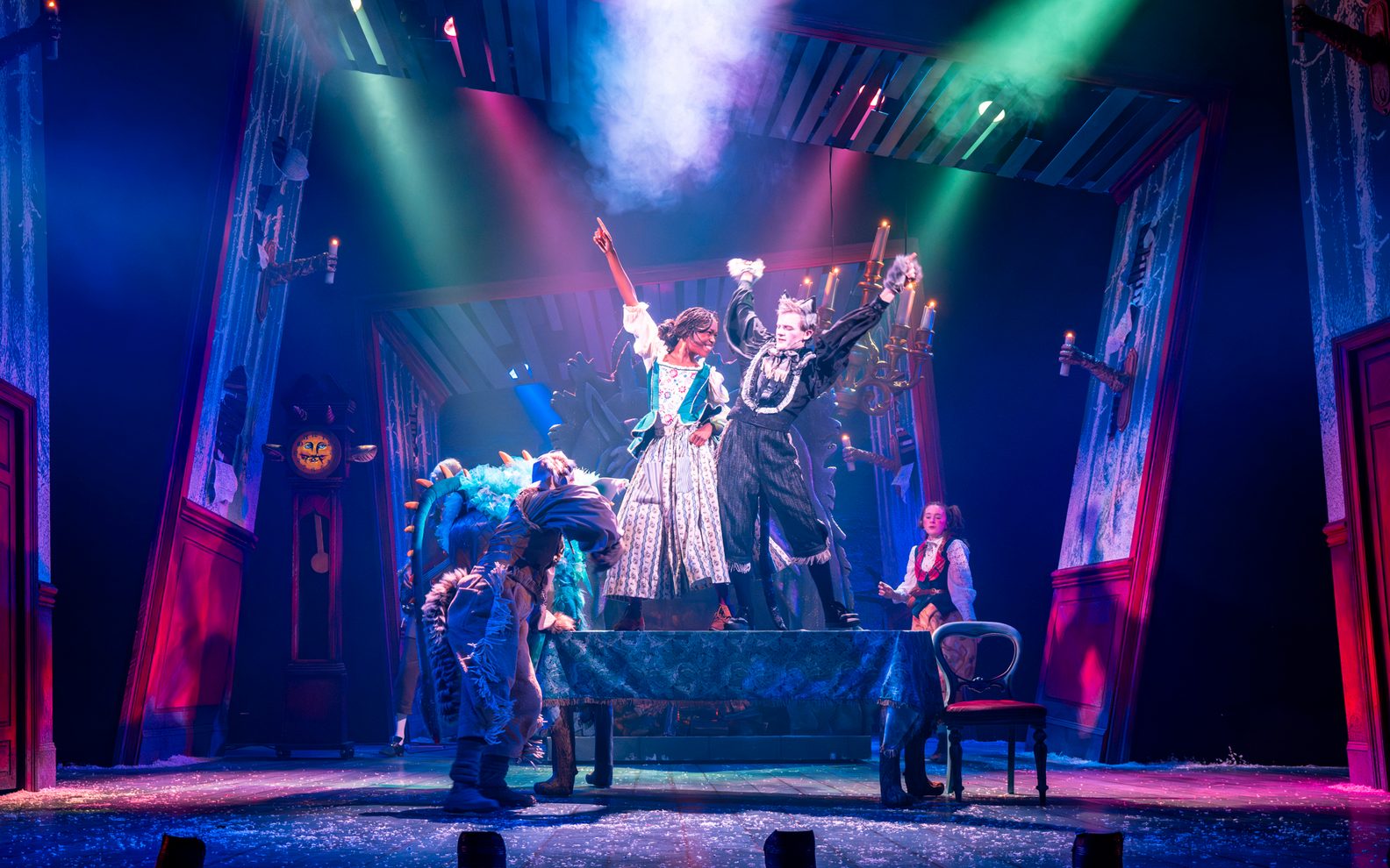 Cast dancing on stage, there are colourful lights