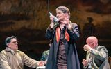 Mary Gapinski holding a microphone on stage in The Long Drop
