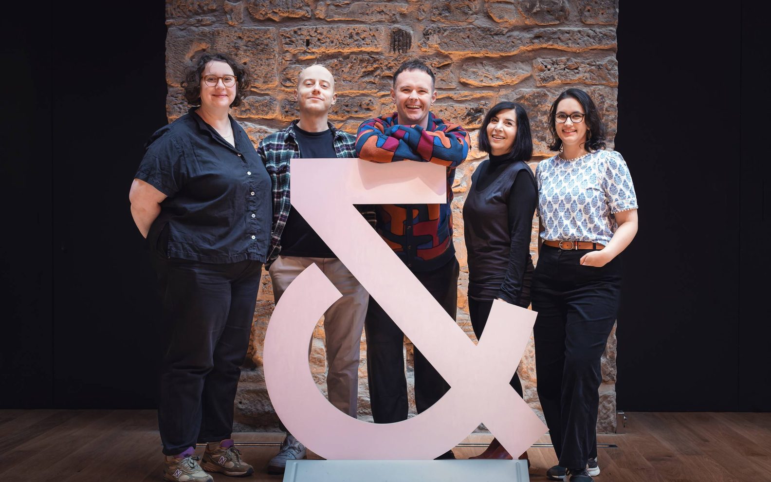 Group of associates artists stading infront of our ampersand