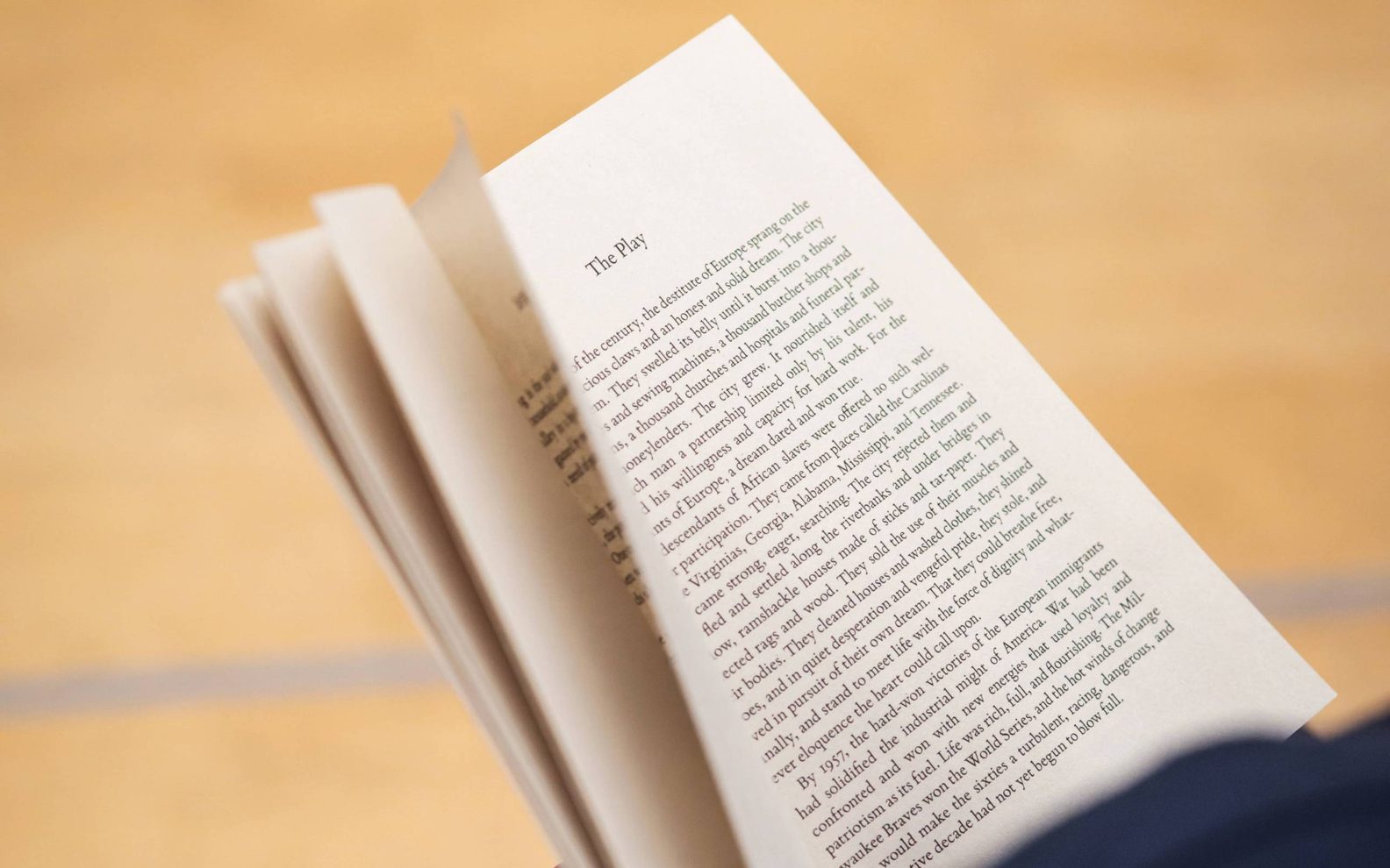 A play reading session. An open book being held in a person's hands.