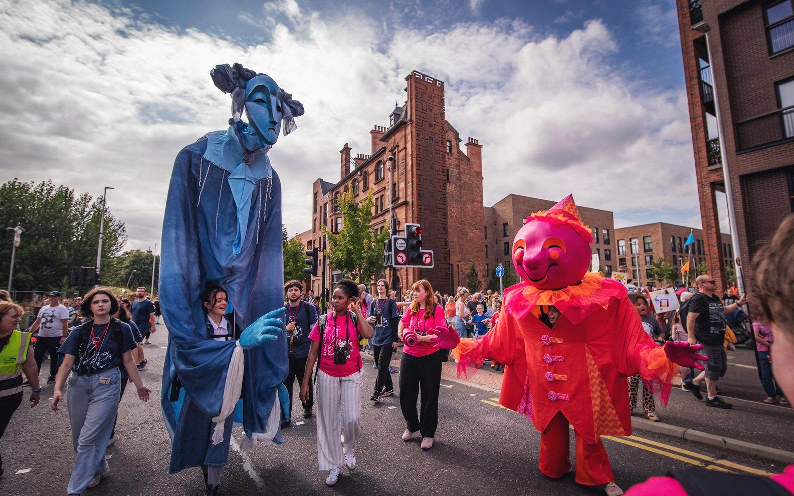 Two large puppets of Comedy and Tragedy leading a procession.
