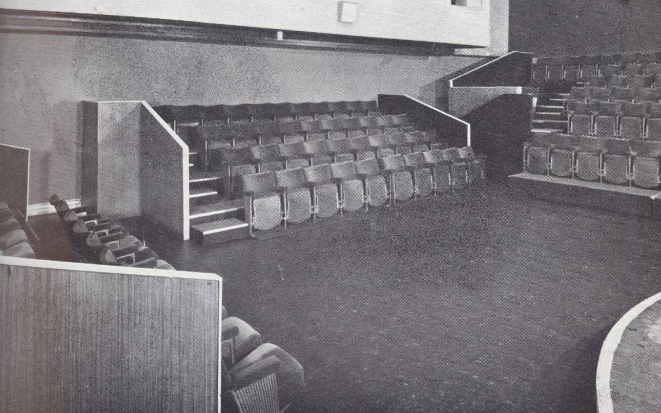 The interior of the Close Theatre. A small stage surrounded on three sides by four rows of seats.