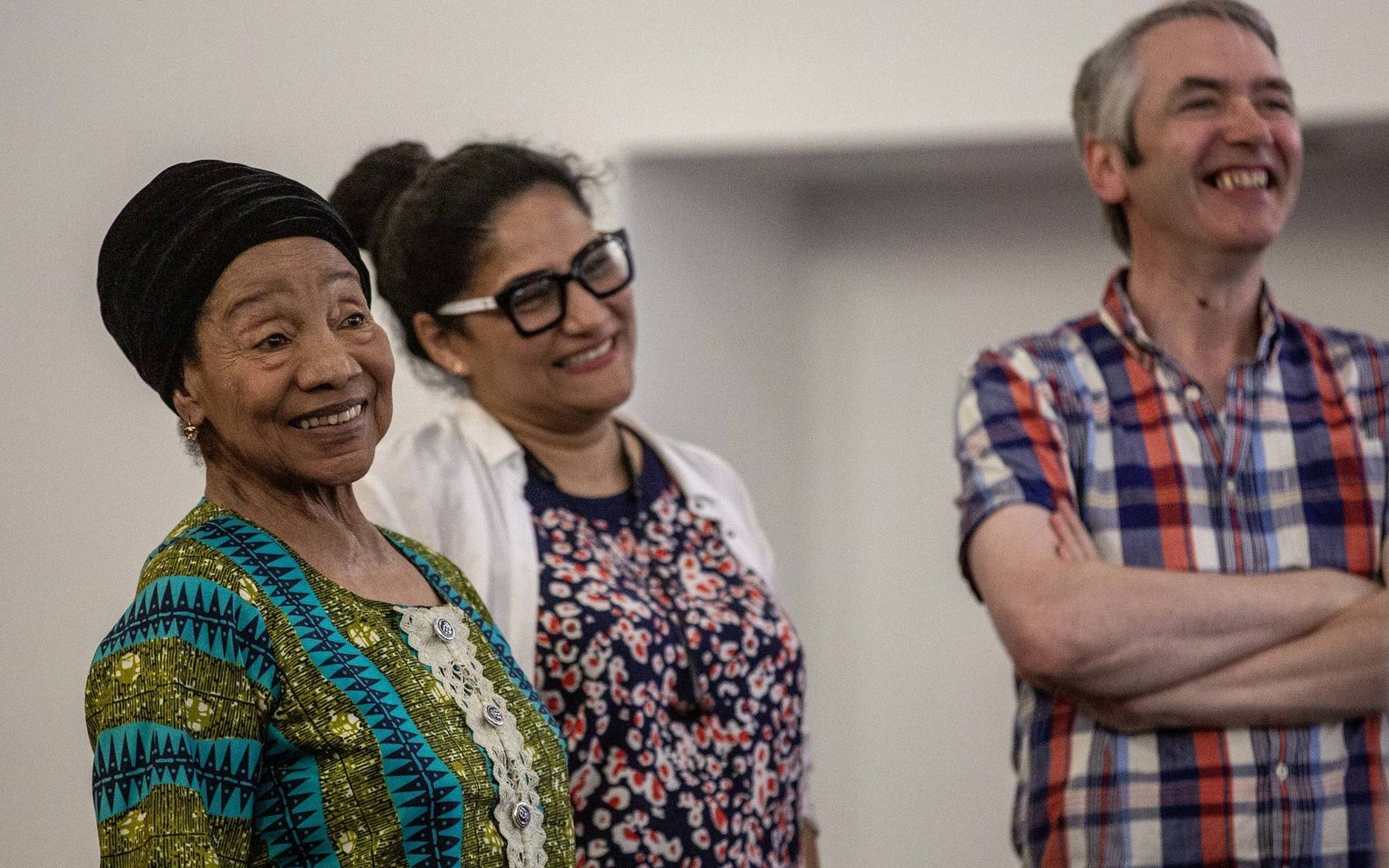 Three adults standing and smiling.